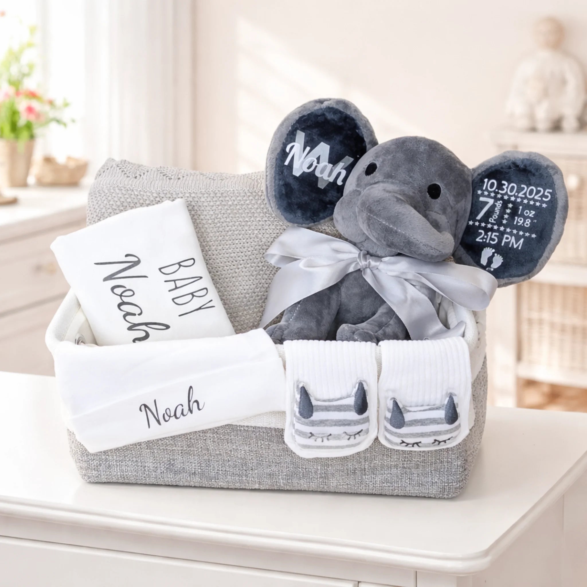 Personalized baby gift basket with gray elephant plush, blanket, brush set, bib, and name Noah.