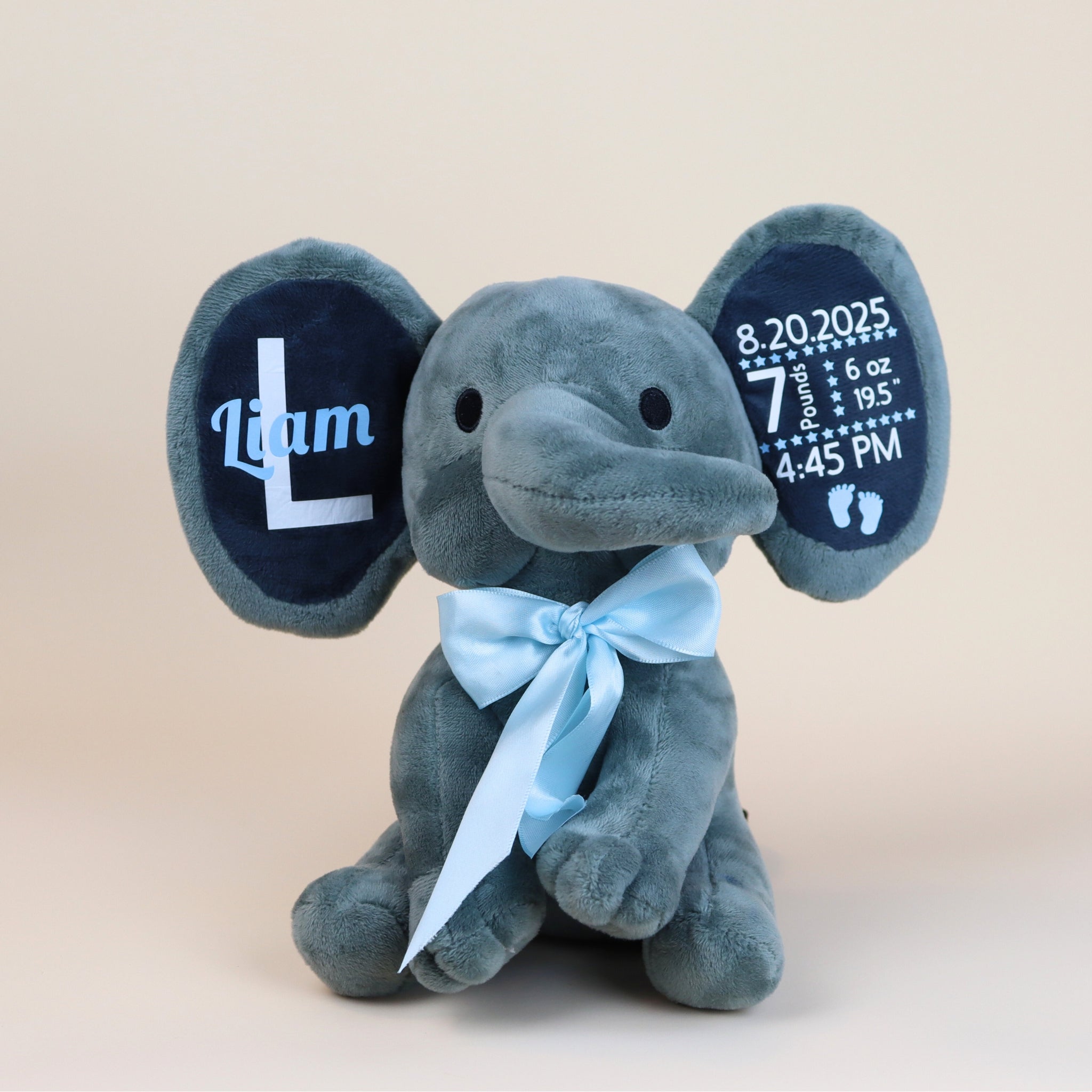 Gray plush elephant toy with personalized details on a beige background