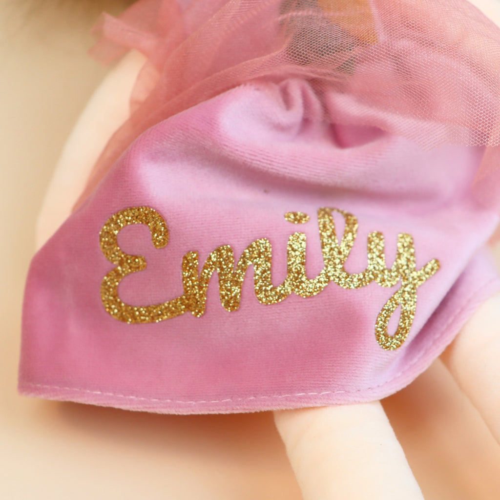 Close-up of floral headband and custom name on plush doll.