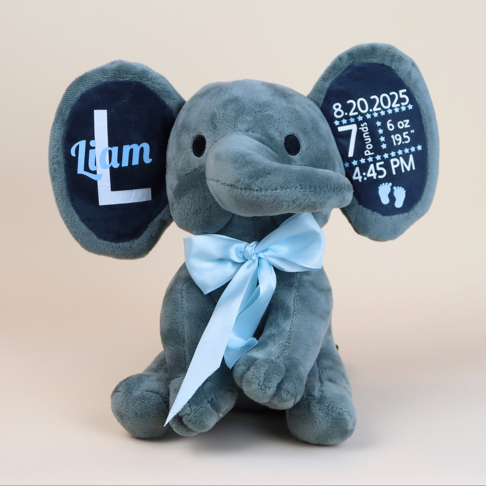 Gray plush elephant toy with personalized details on a beige background